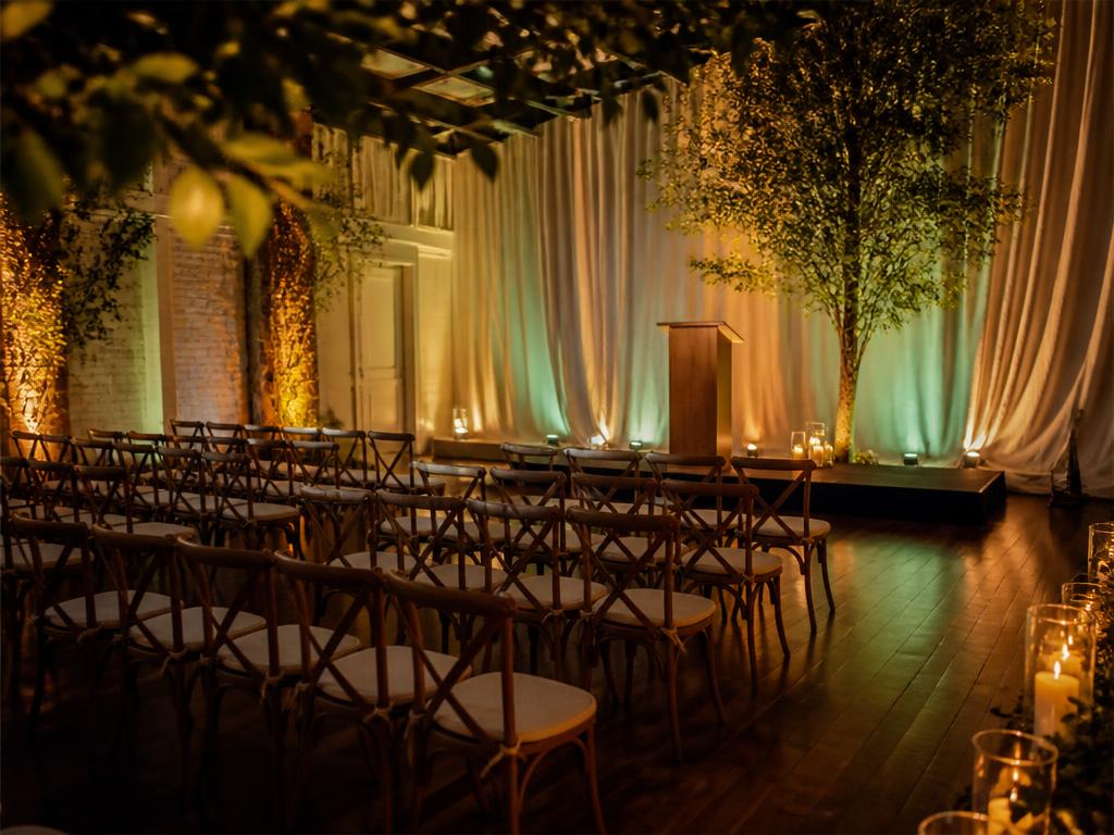 An intimate venue set with rows of wooden chairs facing a small stage, lit with warm atmospheric lighting